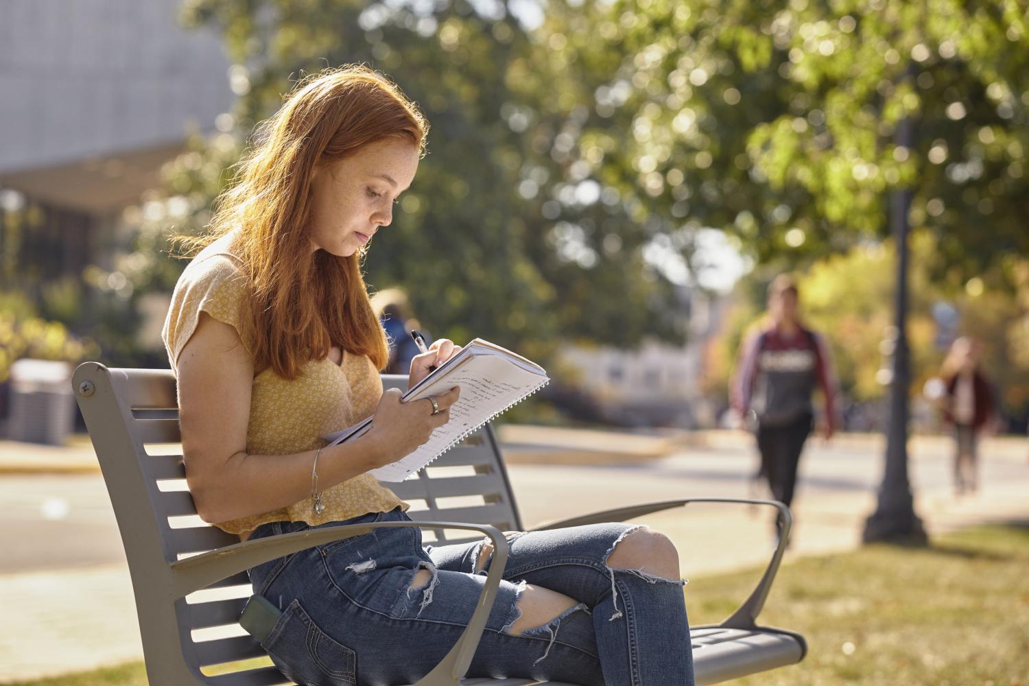 一位<a href='http://5jp.edidi.net'>全球十大赌钱排行app</a>学院的学生在校园里的长椅上读书.